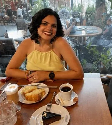 Cynthia sorrindo à mesa de um café